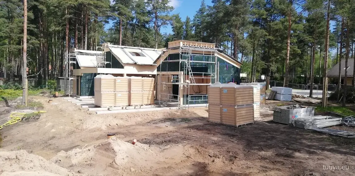 Award-winning timber house under construction with scaffolding among pine trees