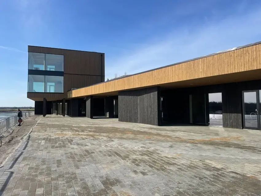 Completed blackened-timber building on a paved waterfront
