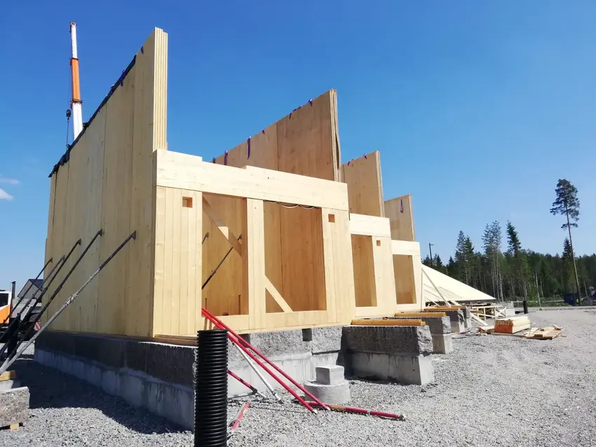 Solid timber wall panels lifted into place by a crane on site
