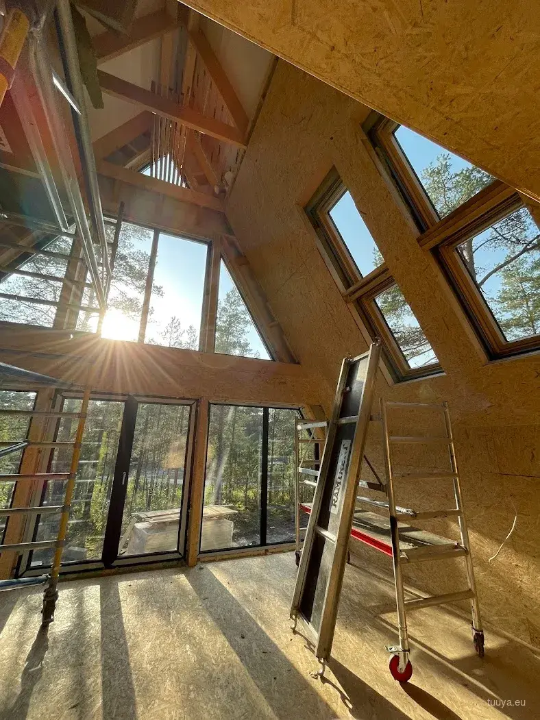 A-frame interior during fit-out with full-height gable glazing and low sun coming through