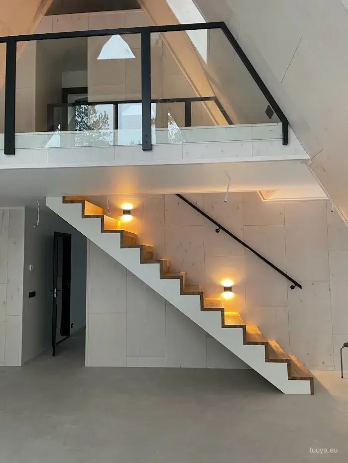 Finished A-frame interior with a timber staircase and a glazed loft
