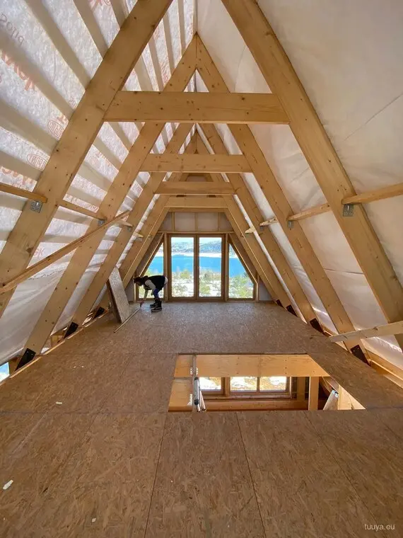 Inside the raised frame: rafter pairs in line, the floor deck down, the gable end still open.