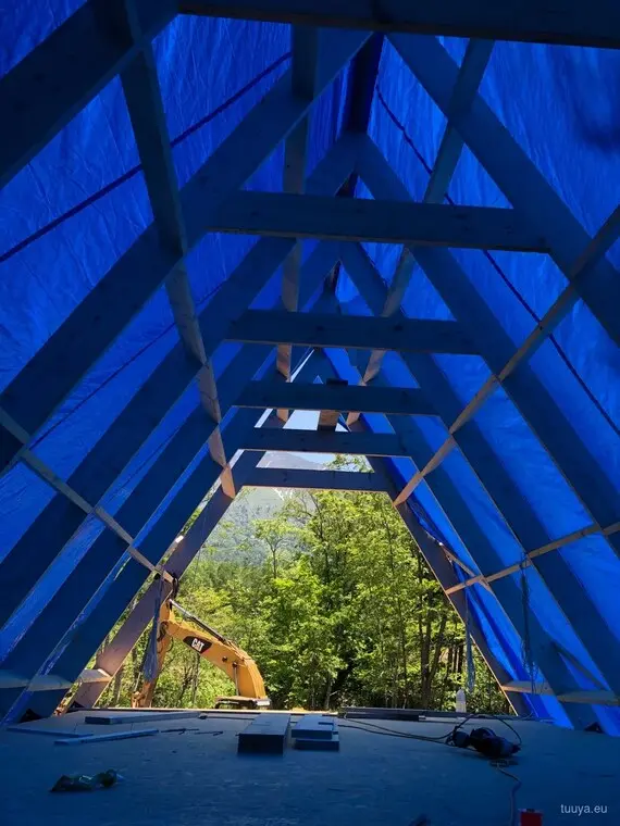 The raised A-frame wrapped against the weather, with the machine that lifted it still on site.