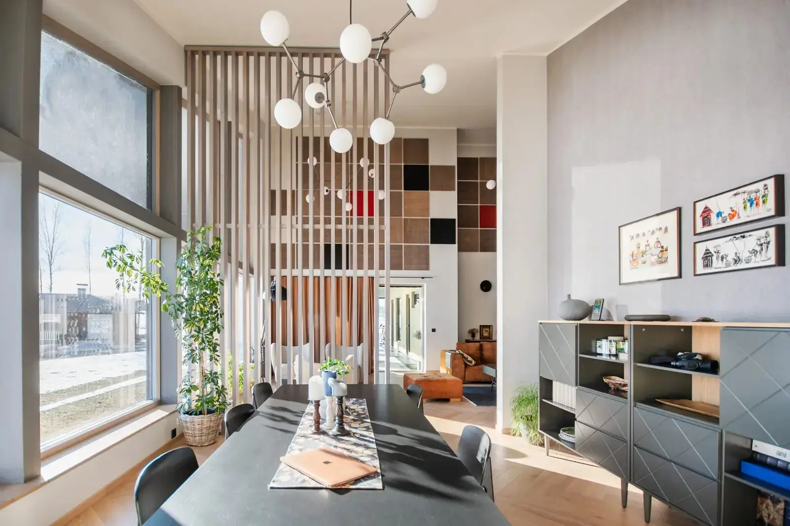 A slatted screen divides the space without blocking the light: daylight from the tall window still reaches the far side.